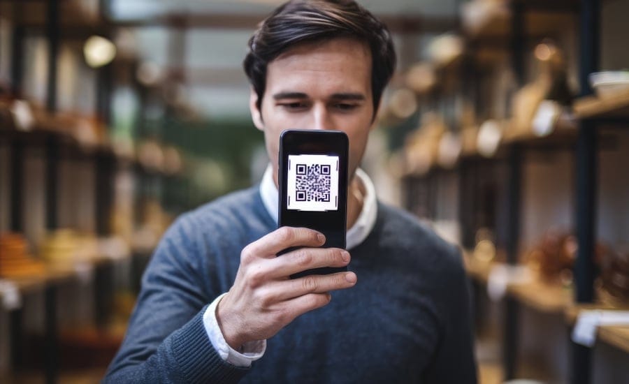 homem com celular na mão mostrando um qo code