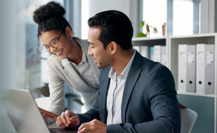 homem e mulher analisando documentos em notebook