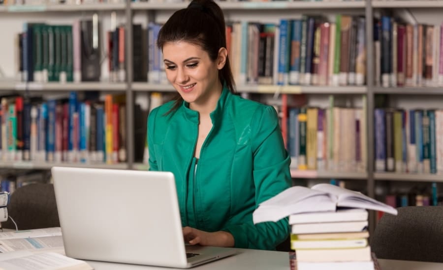 mulher trabalhando em um notebook em uma biblioteca